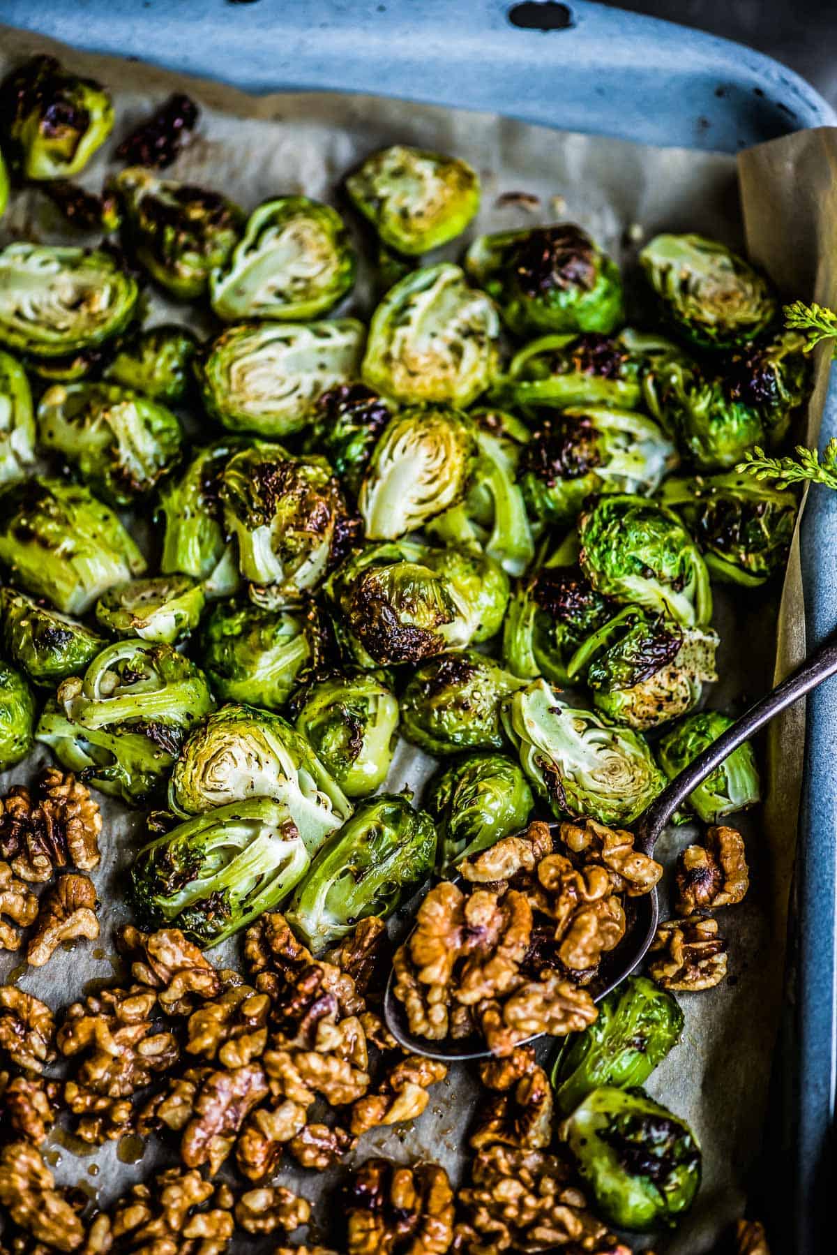 green vegetables roasted on a sheet pan lined with parchment, along with candied walnuts.