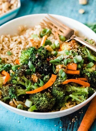 rice bowl recipe with broccoli and carrots in a white bowl with a gold fork.