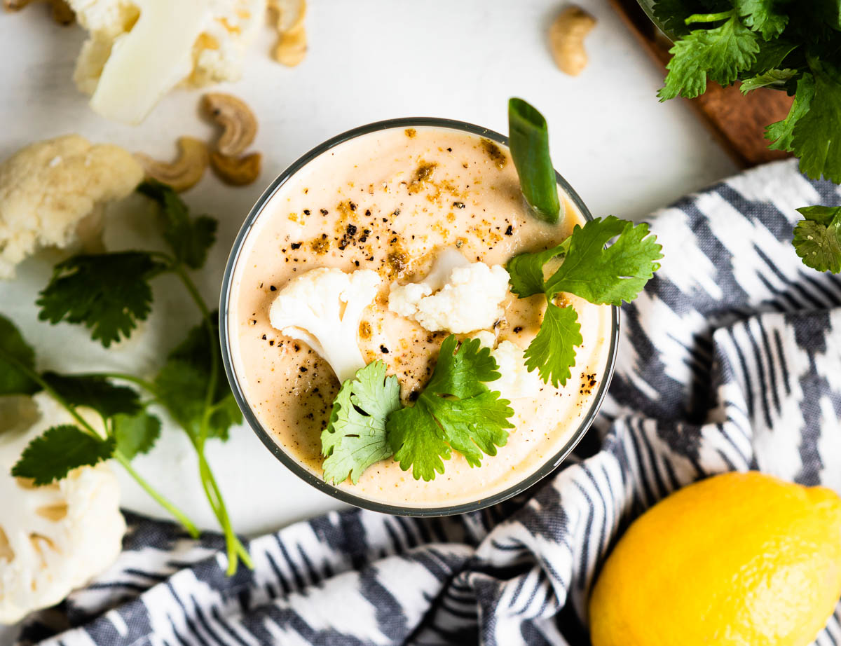 cauliflower smoothie topped with cauliflower florets, green onion, parsley and ground black pepper.