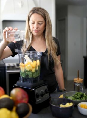 Jen Hansard in her kitchen showing how to make a smoothie with a blender.