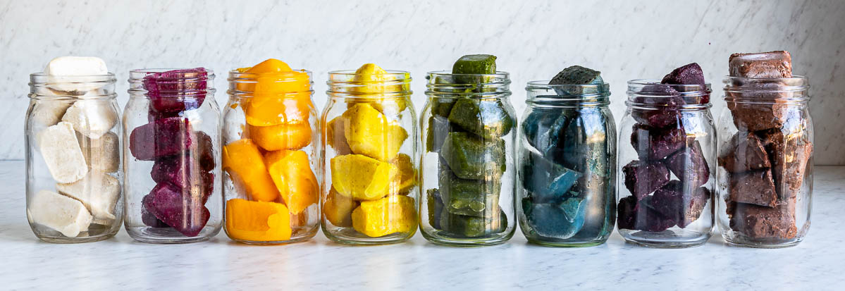 8 glass jars, each filled with different colored frozen smoothie cubes.