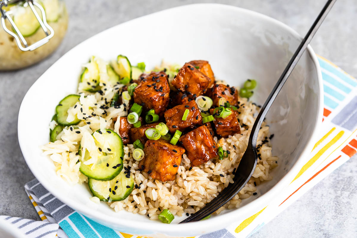 white bowl full of rice and other plant-based ingredients along with a black fork.