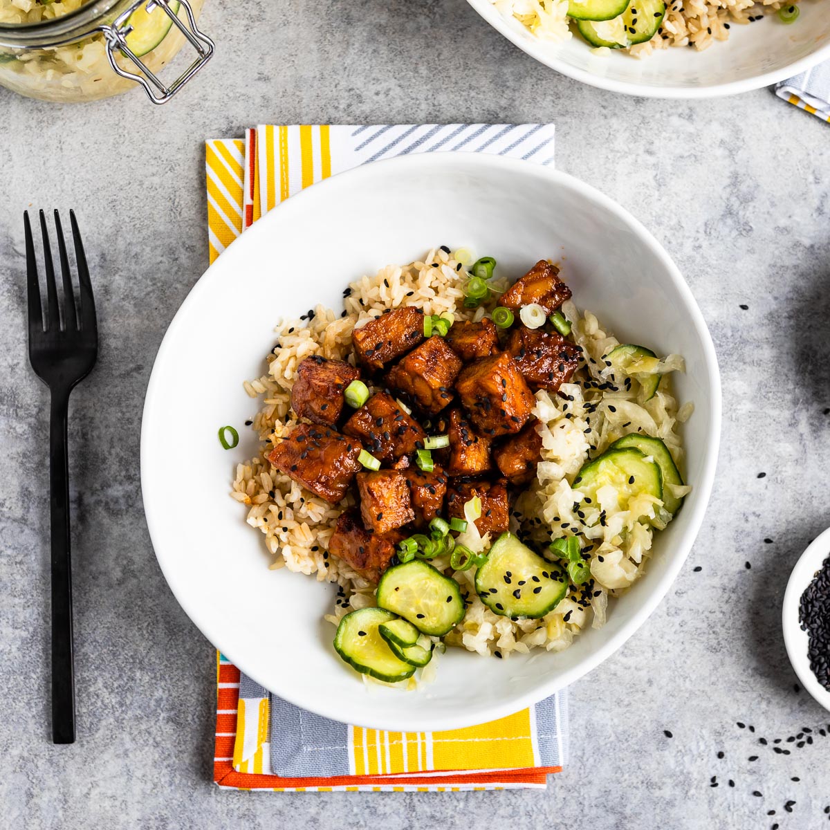 white bowl of spicy marinated tempeh on a colorful napkin.