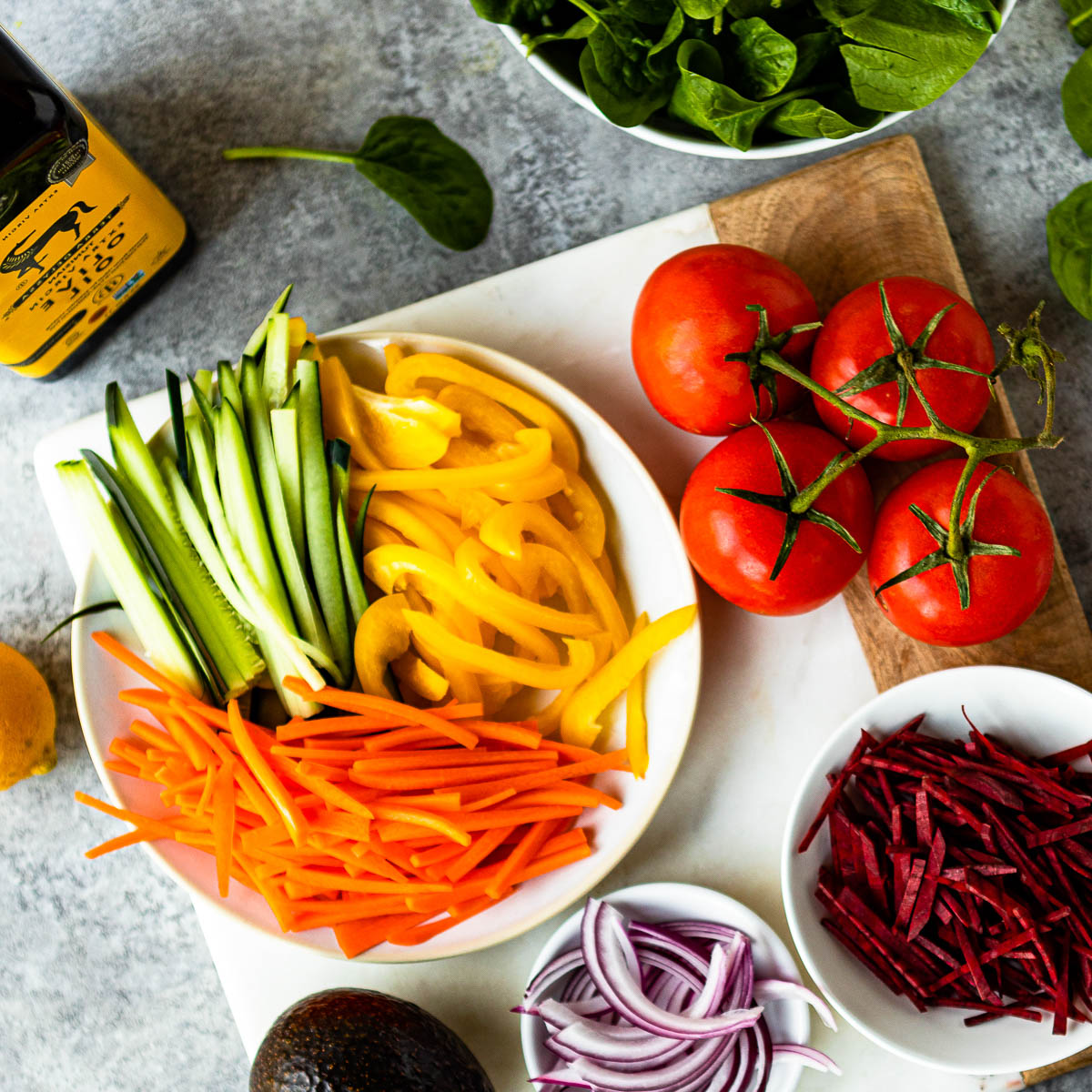 Plate of sliced vegetables on a cutting board surrounded by other veggies, ready for spring meals.