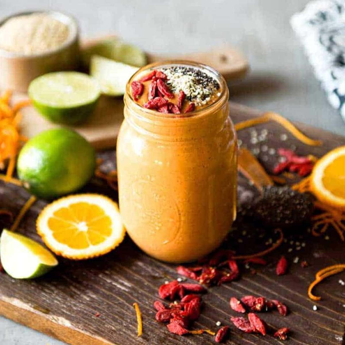 orange superfood smoothie in a glass mug topped with goji berries and hemp hearts.