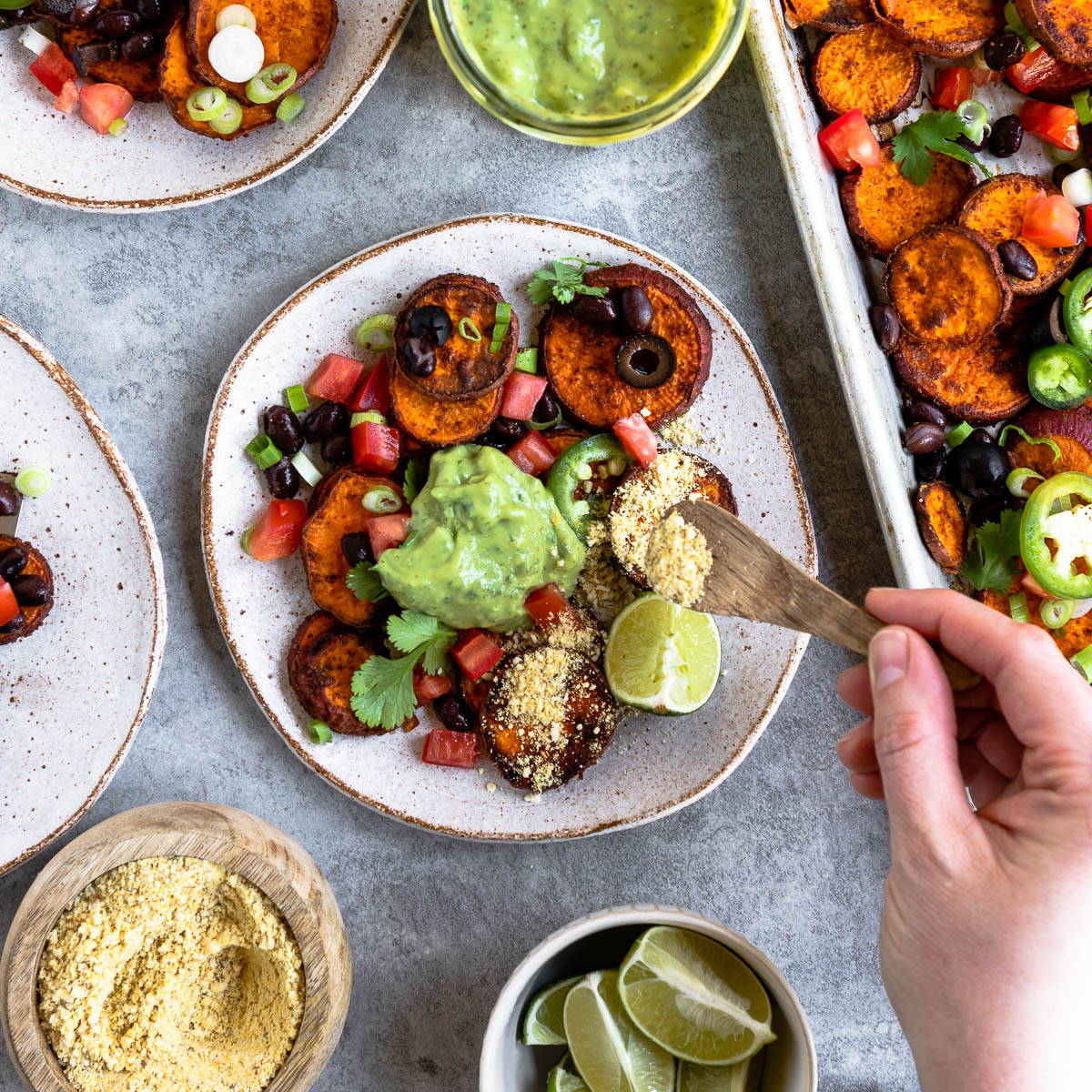 sweet potato nachos topped with avocado crema and vegan Parmesan cheese