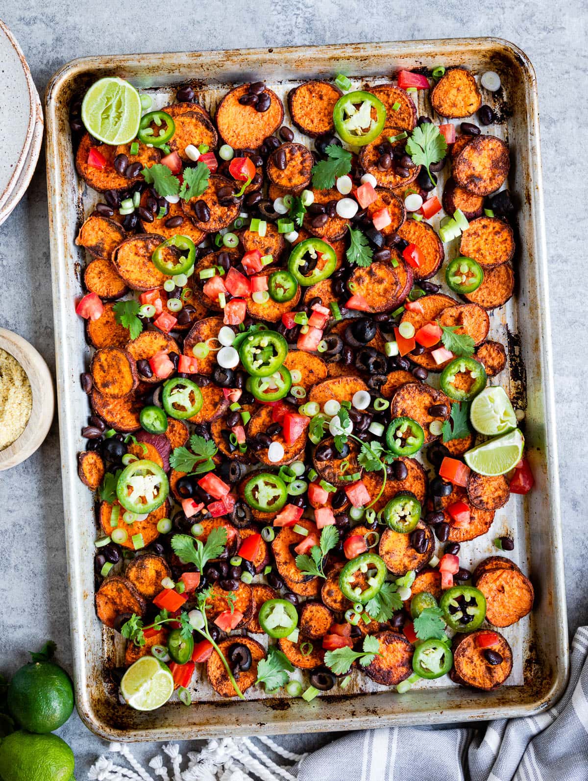 large metal tray full of baked sweet potato nachos with lots of fresh toppings.