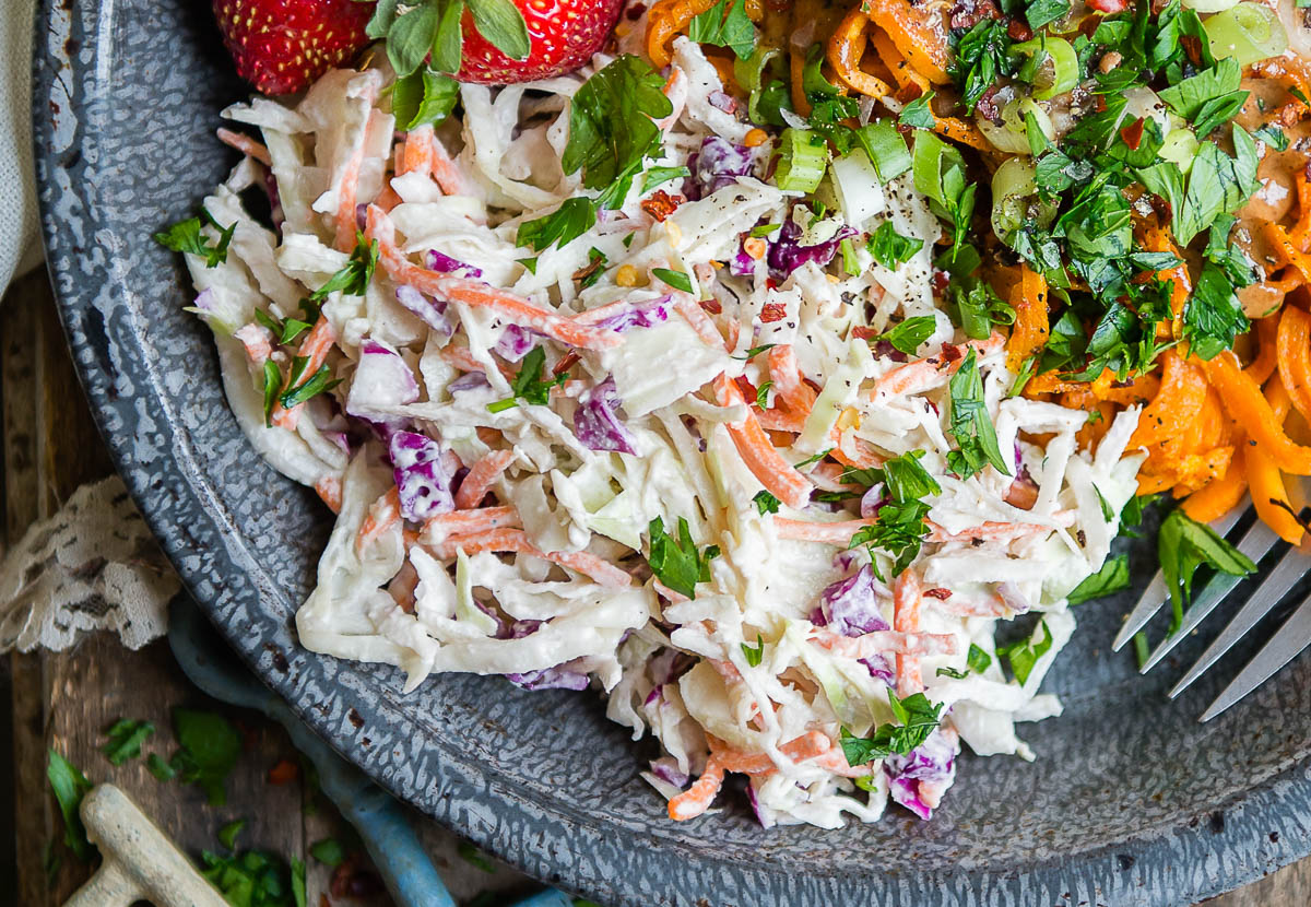 Homemade Sweet Potato Noodles Recipe with vegan coleslaw, sweet potatoes, and parsley in a gray bowl.