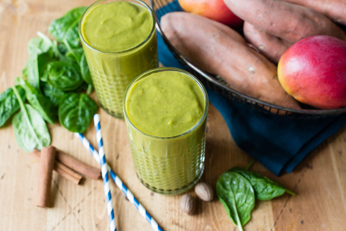 Two sweet potato smoothies with striped straws on the table. 