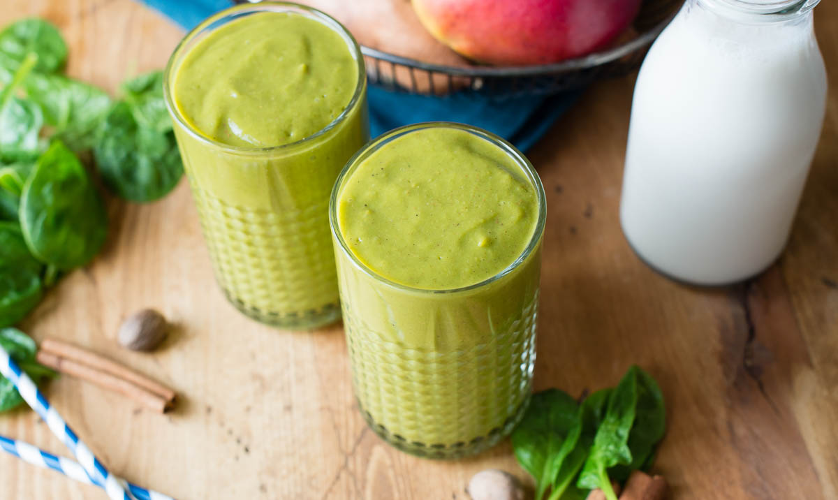 Two sweet potato smoothies in glasses on a rustic wooden table.