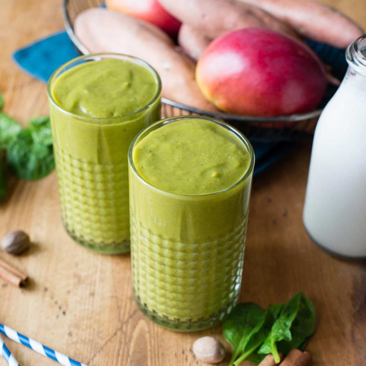 Two glasses of sweet potato smoothie on a table with fresh ingredients.