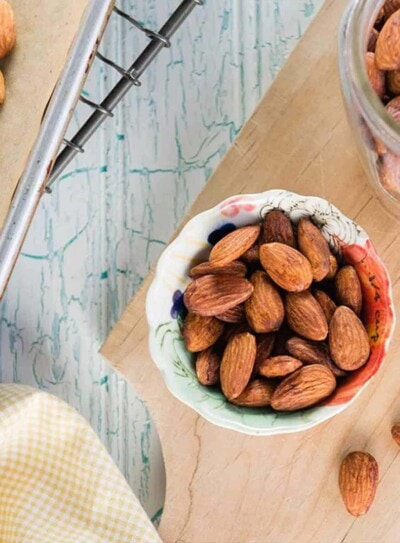 oven roasted almonds in a colorful snack bowl on a wooden tray.