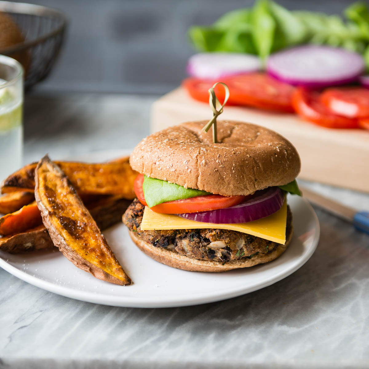 plant-based sandwich on a white plate with sweet potato fries.