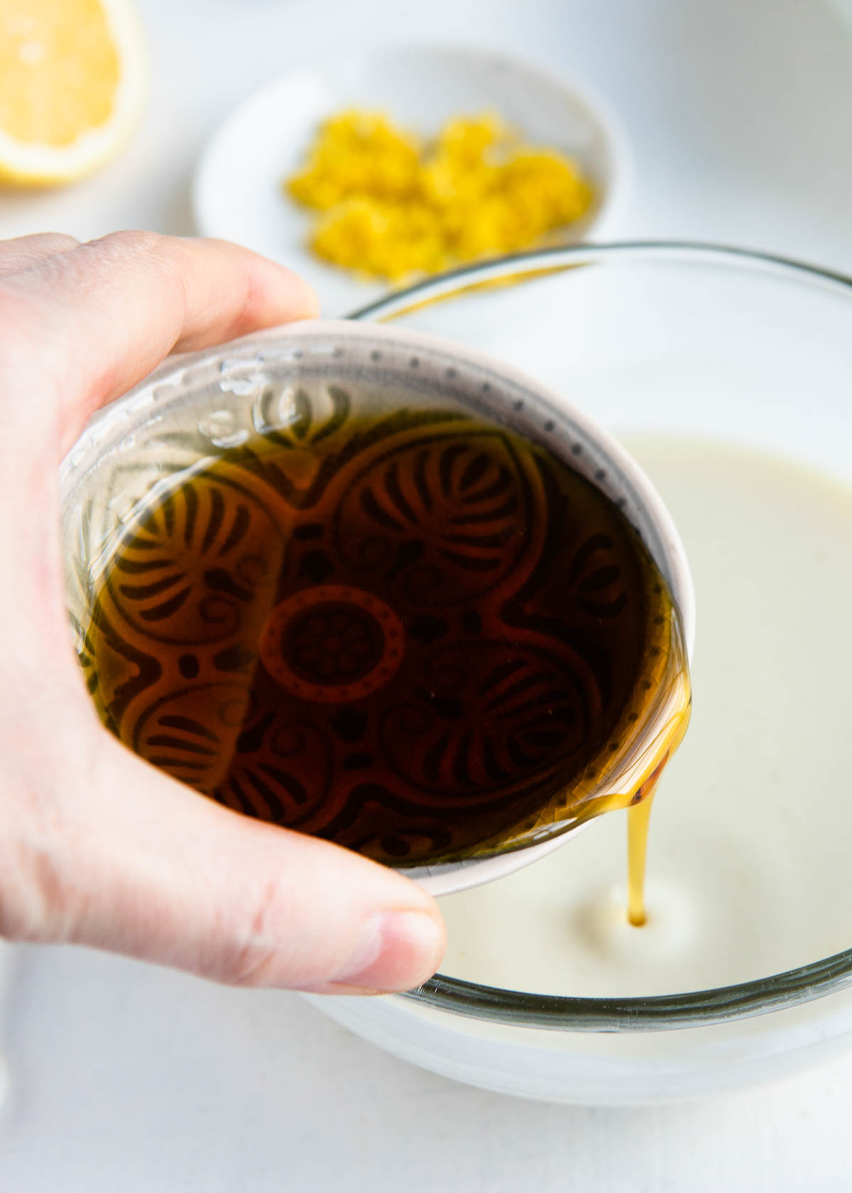 pouring maple syrup into a bowl of wet ingredients.