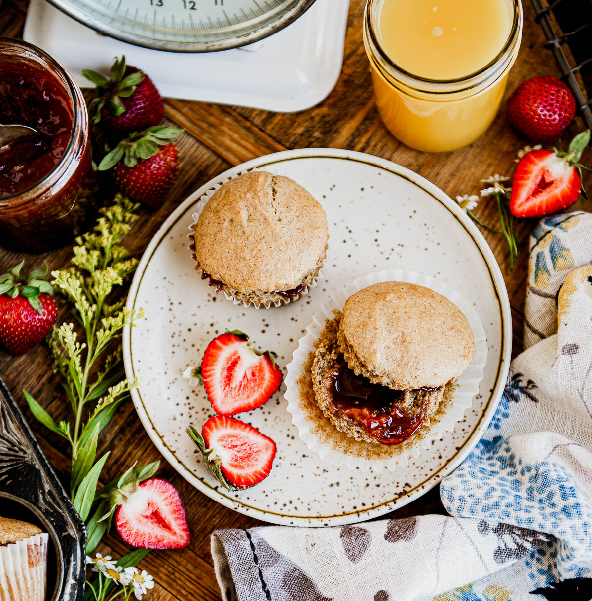 2 strawberry muffins on a white speckled plate surrounded by sliced strawberries.