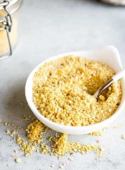 vegan parmesan cheese in a white bowl with a spoon.