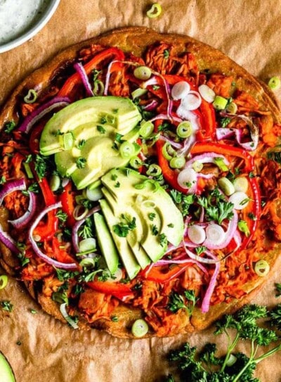 buffalo jackfruit pizza topped with fresh avocado and parsley.