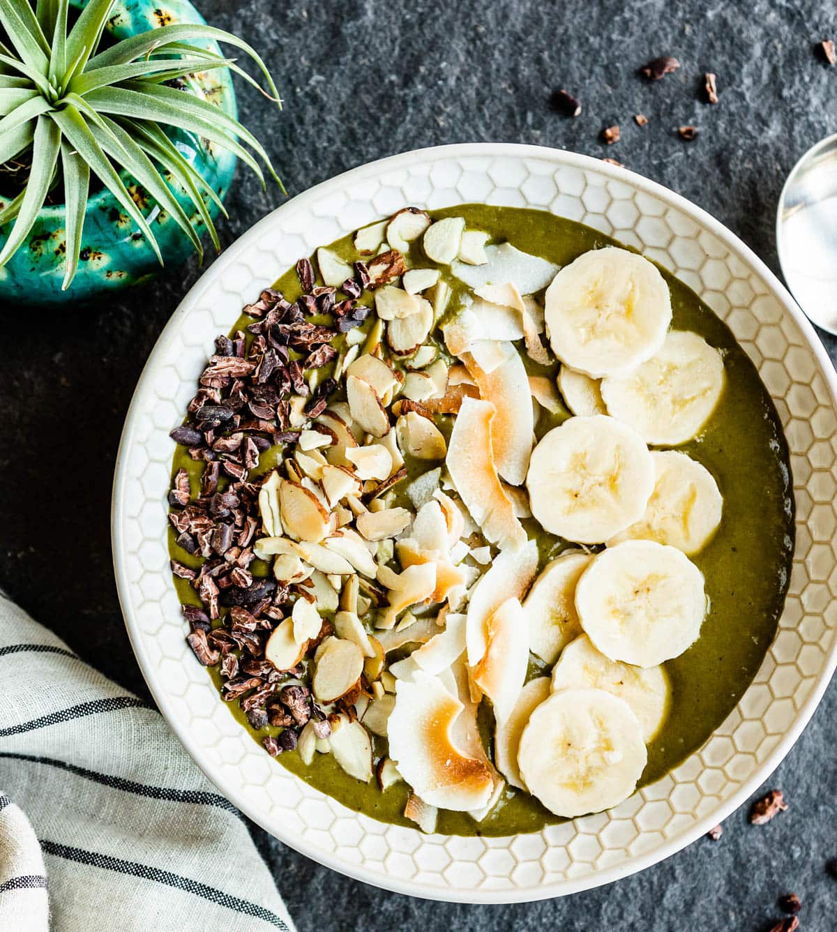 smoothie poured into a bowl with nuts, bananas and cacao nibs.