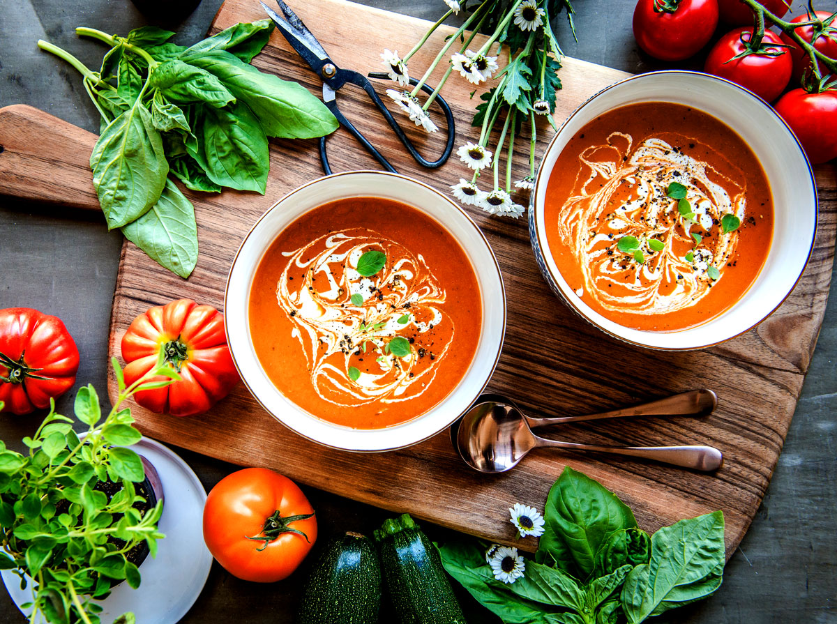 Serving a creamy vegan tomato soup on a rustic wooden cutting board.