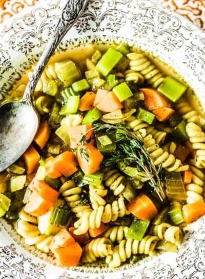 vegetable noodle soup in a festive bowl with a silver spoon.