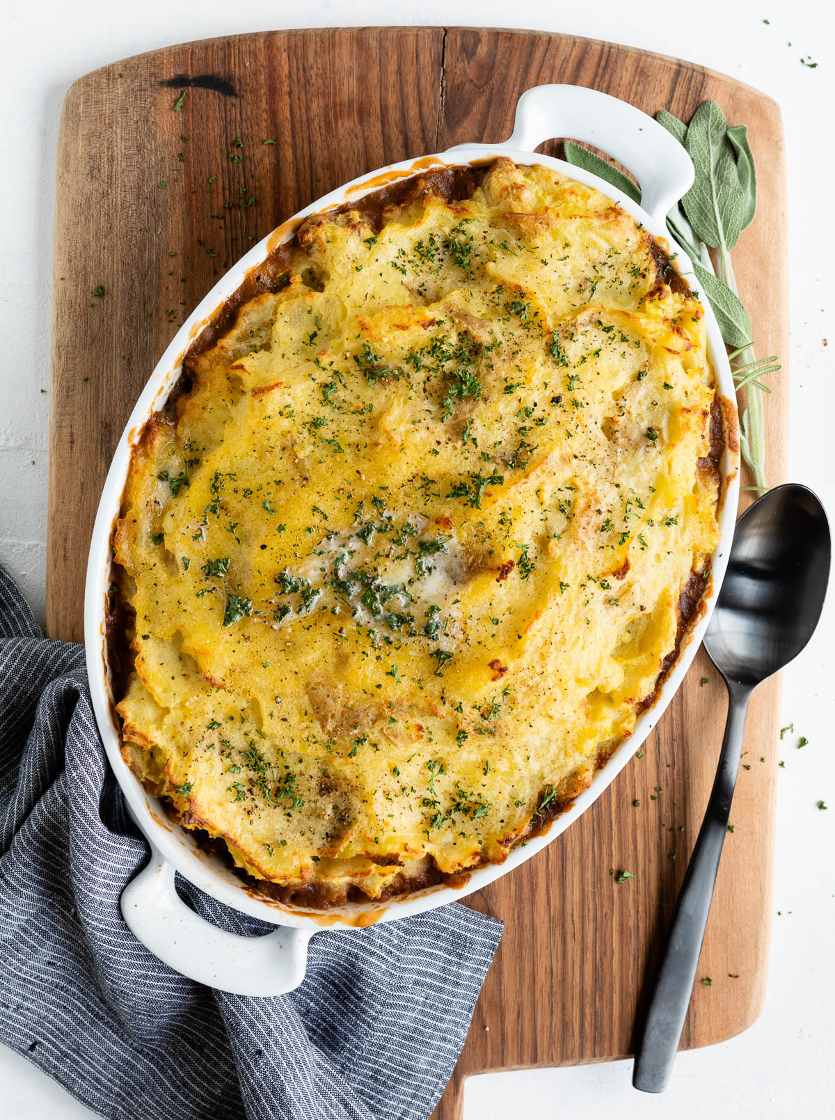 meatless shepherd's pie in white casserole dish next to black serving spoon.