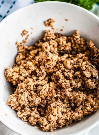 vegan walnut taco meat in a white bowl ready to be scooped with a spoon.