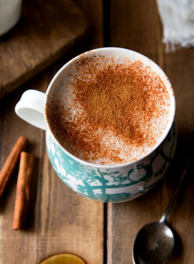 A cozy cup of warm almond milk topped with a sprinkle of cinnamon, served in a rustic white mug.