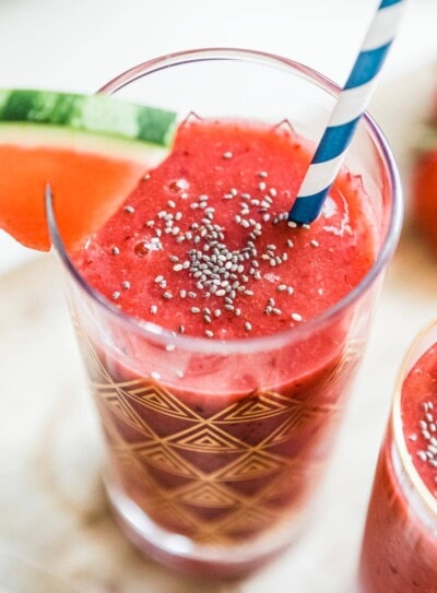 watermelon smoothie in a gold flecked glass with a paper straw.