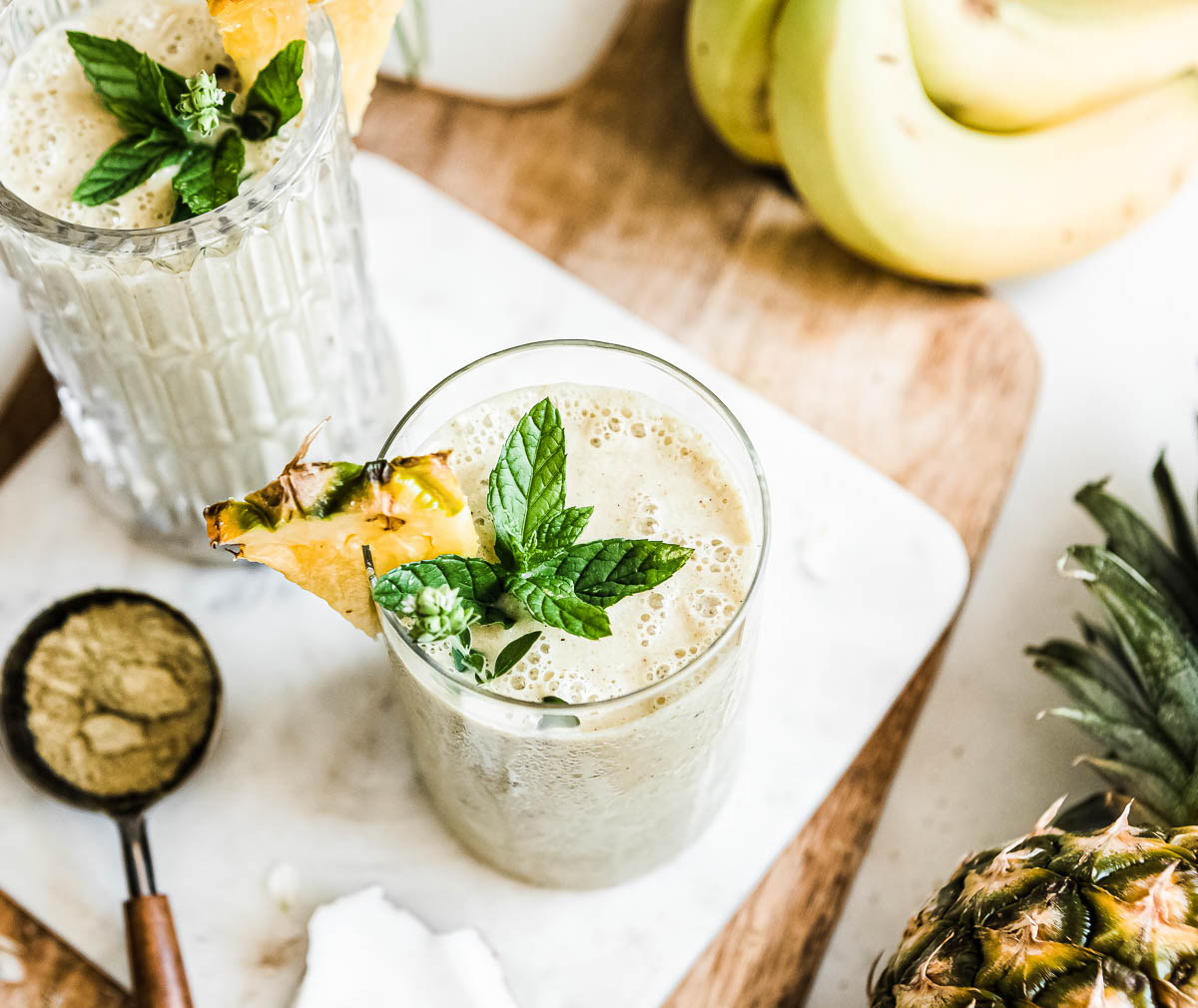 weight gain smoothie in a glass with pineapple and mint on top.