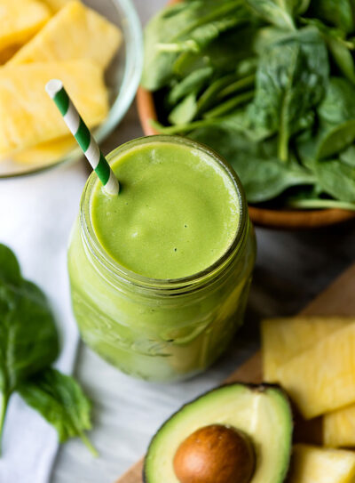 tropical smoothie in glass jar with stripped straw.