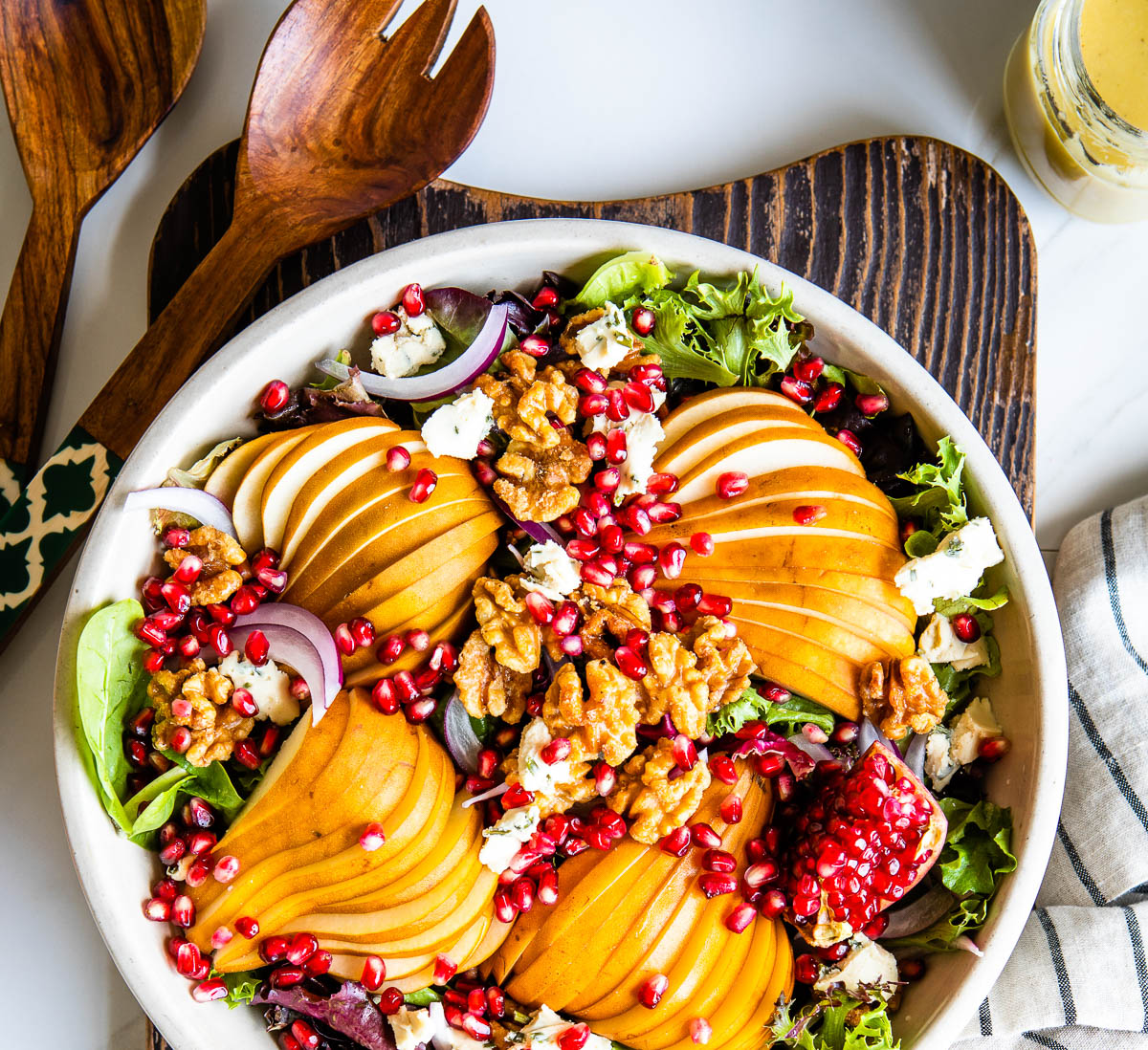 fresh salad on a bed of mixed greens with sliced pears, walnuts, vegan cheese and pomegranate arils.